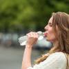 Frau trinkt aus einer Plasteflasche Wasser