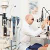 Augenarzt schaut einer Frau mit einem technischen Gerät in die Pupillen