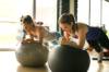 Zwei junge Frauen machen Ellbogenplank auf Fitnessbällen