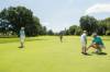 Mann zeigt Buben das Golfen auf dem Grün eines Golfplatzes