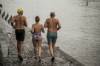 Drei Winterschwimmer in Badekleidung auf dem Weg zum Rhein in Basel