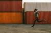 Mann joggtt auf Lagerplatz mit Containern