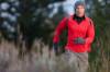 Mann joggt im Winter mit Handschuhen und Mütze über Feld und Flur
