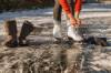 Frau bindet sich ihre weissen Schlittschuhe auf Natursee zu