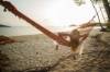 Blonde Frau geniesst am tropischen Strand in einer Hängematte liegend den Sonnenuntergang