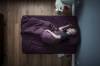 Graumellierter, bärtiger Mann schläft auf der Seite liegend in lila Bettwäsche, von oben fotografiert