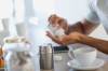 Mann beim Kaffeetrinken schüttet sich Tabletten aus einer Kunststoffdose in die geöffente Hand