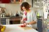 Frau schneidet in ihrer Küche auf einem Holzbrett eine Tomate in Scheiben