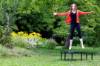 Frau in roter Jacke hüpft im Garten auf einem Mini-Trampolin