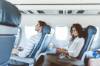 Mann und Frau sitzen hintereinander im Flugzeug