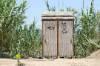 Schilfbedeckte Toilettenkabinen für Männer und Frauen an einem tropischen Strand