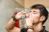 Junger Mann mit Lederschmuckbändern verabreicht sich ein Medikament un die Nase