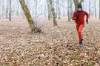 Jogger im rotem Trainingsanzug läuft durch Herbstwald